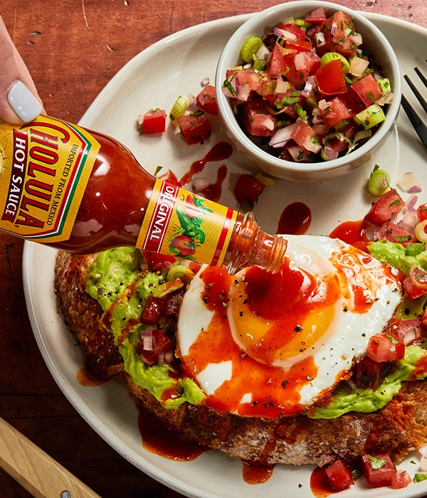 avocado toast with fried egg, topped with cholula hot sauce
